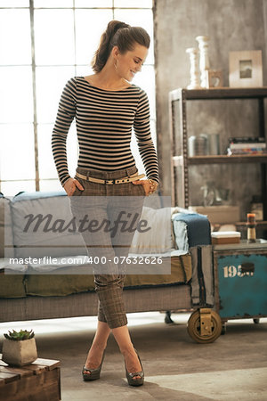 Full length portrait of young woman standing in loft apartment