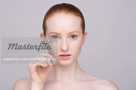 Portrait of young woman, curling eyelashes