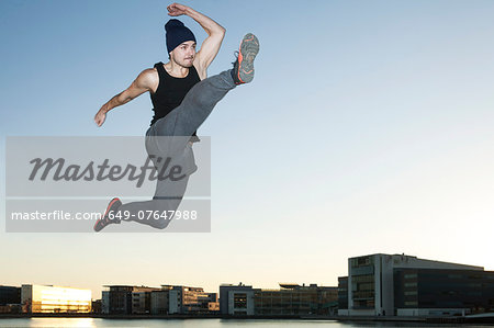 Mid adult man jumping mid air, Copenhagen harbor, Denmark
