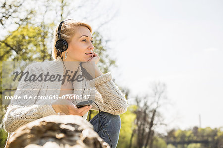 Young woman listening to headphones in forest