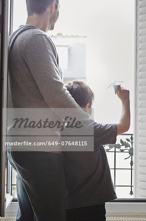Boy launching paper plane from window