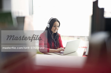 Young woman wearing headphones using laptop