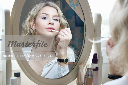 Teenage girl looking in mirror, applying make-up