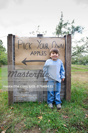 Portrait of cute boy in front of pick your own sign