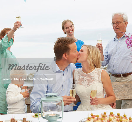 Mid adult couple kissing and making a toast with group of friends