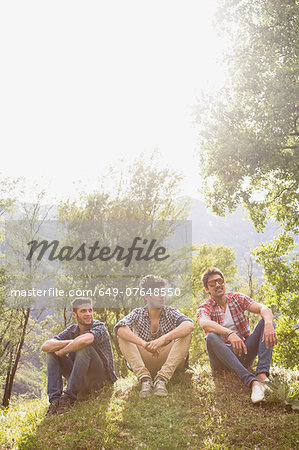 Three young men sitting on grass