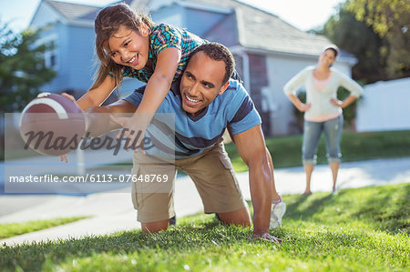 Father and daughter playing football in yard
