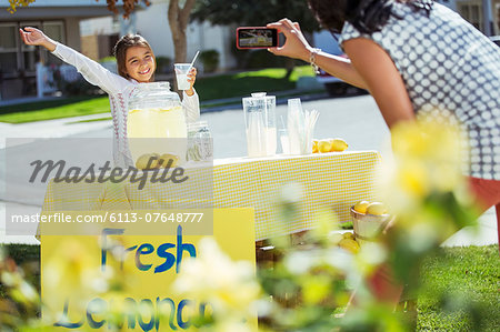 Mother photographing daughter at lemonade stand