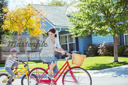 Mother and daughter riding bikes in street