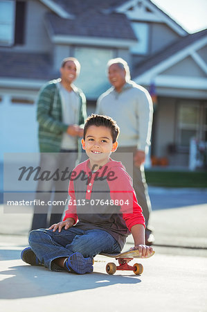 Portrait of smiling boy on skateboard in driveway