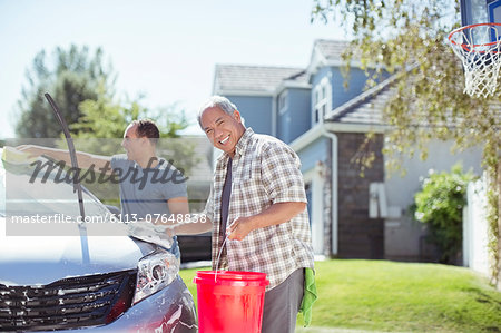 Portrait of smiling father and son washing car in driveway