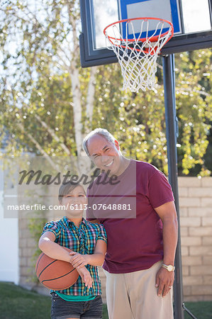Portrait of grandfather and granddaughter playing basketball