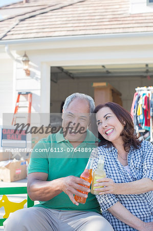 Portrait of happy couple toasting soda bottles at garage sale