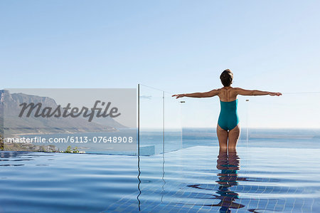 Woman basking in infinity pool overlooking ocean