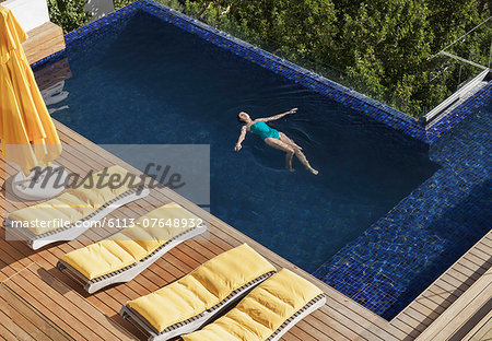 Woman floating in luxury swimming pool