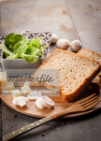 Sliced brown bread,Comté,raw button mushrooms and baby spinach leaves