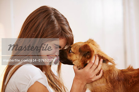 Young woman having face licked by pet dog