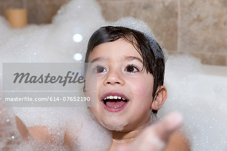 Young boy trying to catch bubble in bubble bath