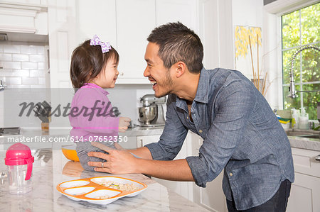 Mid adult man with toddler daughter on kitchen counter