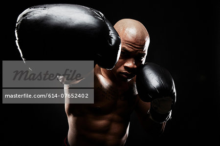 Boxer with black boxing gloves punching towards camera
