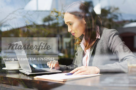 Young female businesswoman using laptop in cafe Young female businesswoman using laptop in cafe