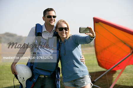 Couple taking selfie, hang glider in background
