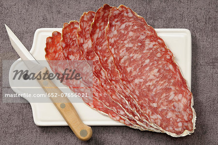 Slices of large dried sausage on a chopping board