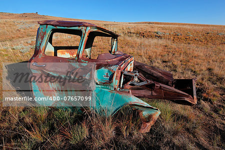 Wreck of a rusty old pickup truck out in the field