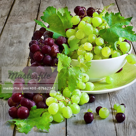 Ripe green and red grape in ceramic bowl. Selective focus.