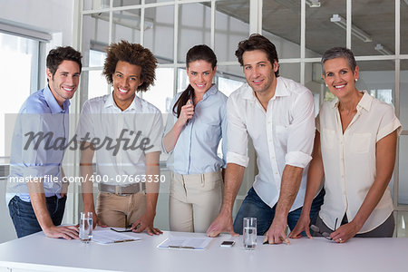 Casual business team having a meeting smiling at camera in the office