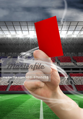Hand holding up red card against stadium full of usa football fans