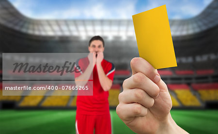 Hand holding up yellow card against stadium full of germany football fans with player