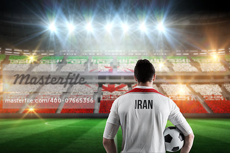 Iran football player holding ball against stadium full of iran football fans