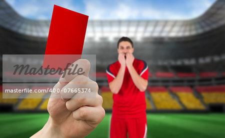 Composite image of hand holding up red card to player against stadium full of germany football fans