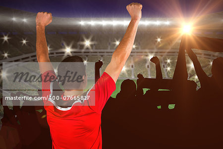 Excited football player cheering against large football stadium with lights