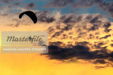 silhouette of unidentified skydiver parachutist on sky with sunset