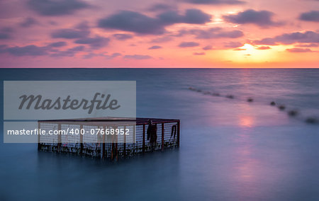 Seascape and Empty Cage at Colorful Cloudy Sunset