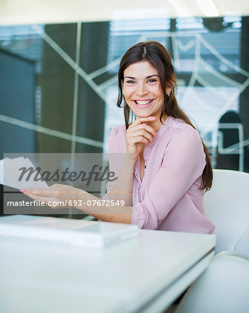 Portrait of smiling young businesswoman with documents at conference table