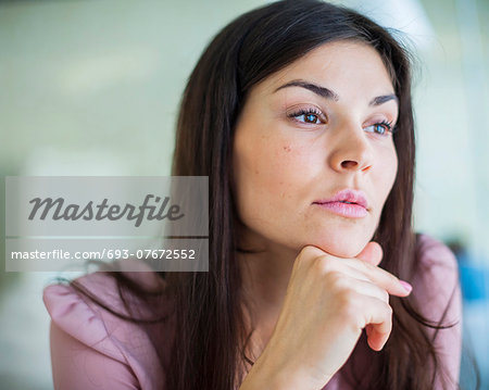 Thoughtful young businesswoman looking away in office