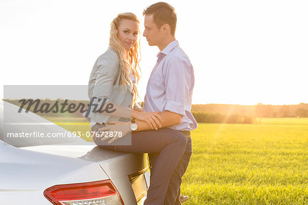 Side view of romantic young couple by car at countryside