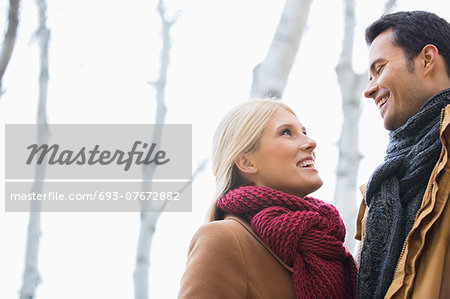 Low angle view of couple looking at each other in park during autumn