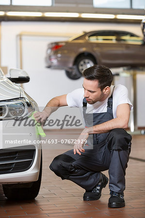 Full length of automobile mechanic cleaning car in workshop Full length of automobile mechanic cleaning car in workshop