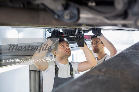 Maintenance engineers repairing car in workshop
