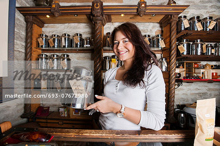 Portrait of smiling salesperson displaying tea container in store