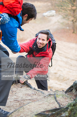 Hiker helping friend while trekking in forest