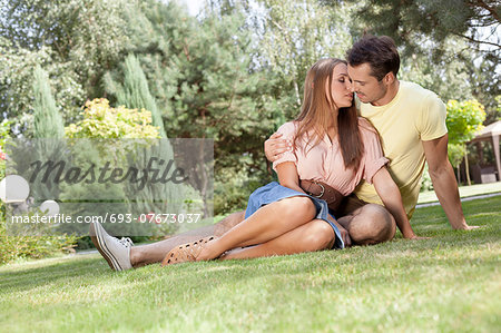 Full length of romantic young couple relaxing in park