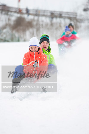 Young couple enjoying sled ride on snow covered slope Young couple enjoying sled ride on snow covered slope
