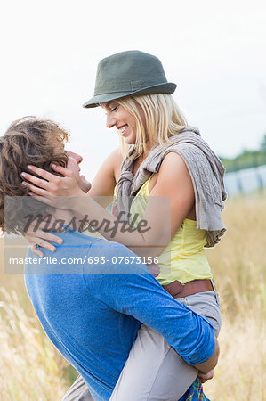 Romantic man carrying woman in field