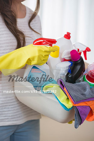 Midsection of woman carrying basket of cleaning supplies at home