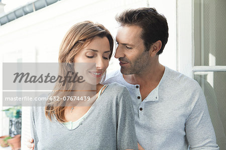 Couple embracing by open window